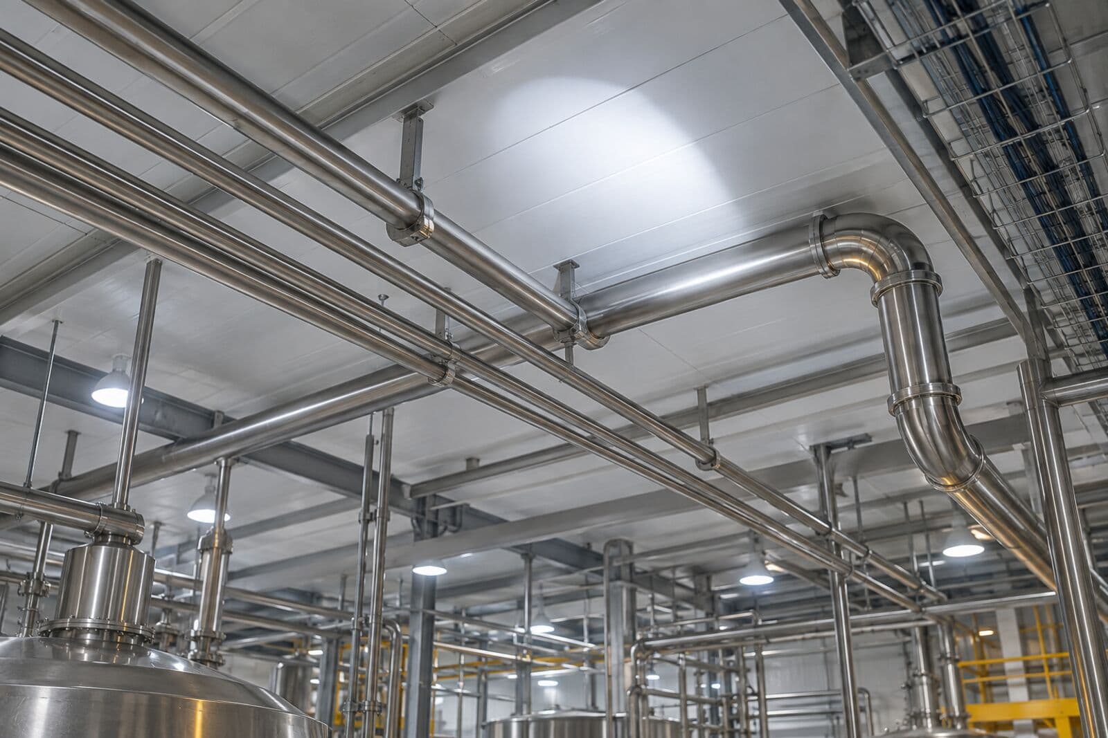 Clean stainless overhead pipes in a food plant lit by a flashlight beam